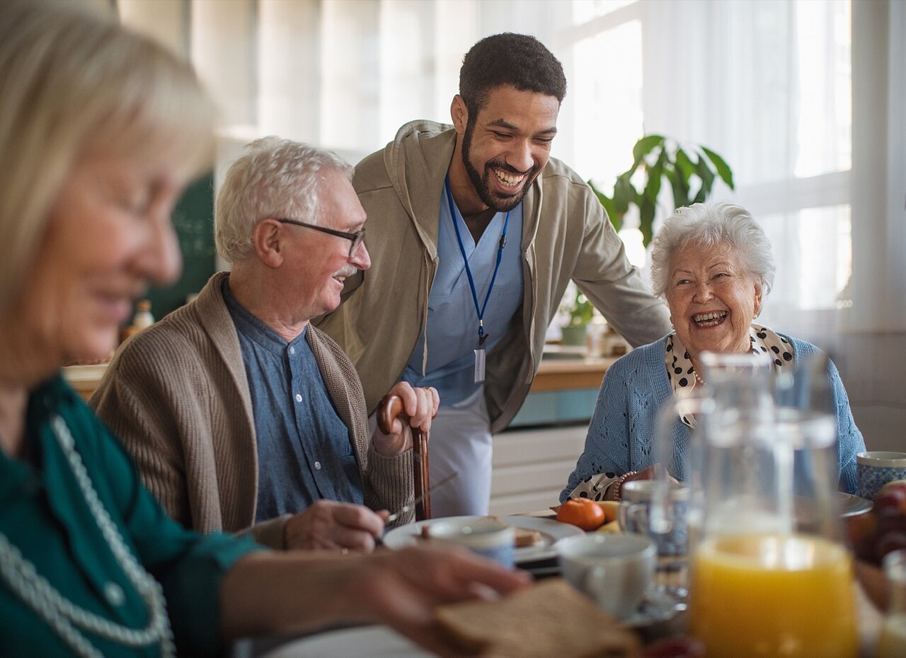 Eine Betreuungsgruppe von Senior:innen frühstückt in einer Tagespflegeeinrichtung der AWO Mönchengladbach und erhält Unterstützung.